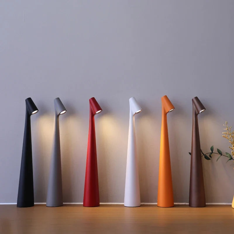 Lámpara de mesa LED regulable con carga USB y control táctil, diseño minimalista y portátil disponible en seis colores vibrantes. 0