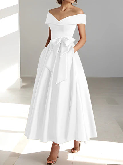 Vestido de madrina de boda en satén fucsia, largo al tobillo, con hombros descubiertos y prácticos bolsillos. 1